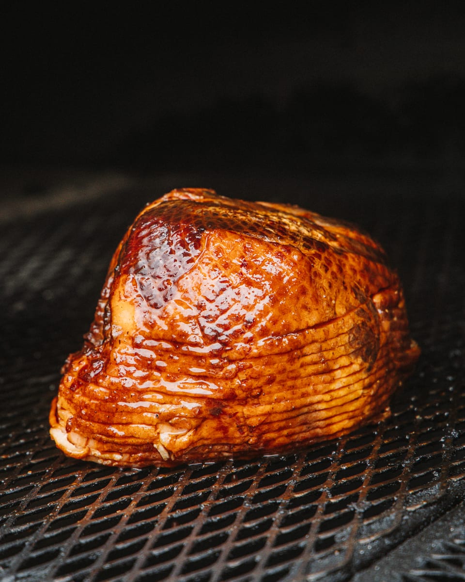 A glazed spiral-sliced ham on the pit grate