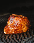 A glazed spiral-sliced ham on the pit grate
