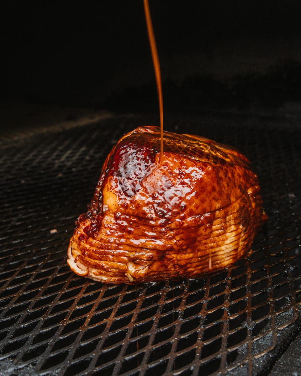Glaze poured over a spiral-sliced ham on the pit