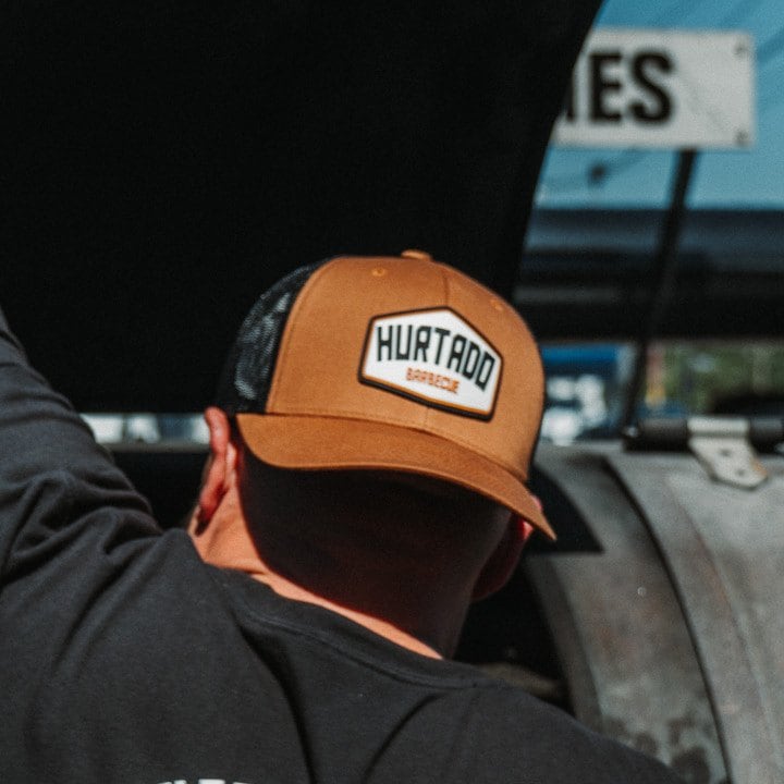 Hexagon Patch Trucker Hat in tan with a black mesh back, worn at the smoker