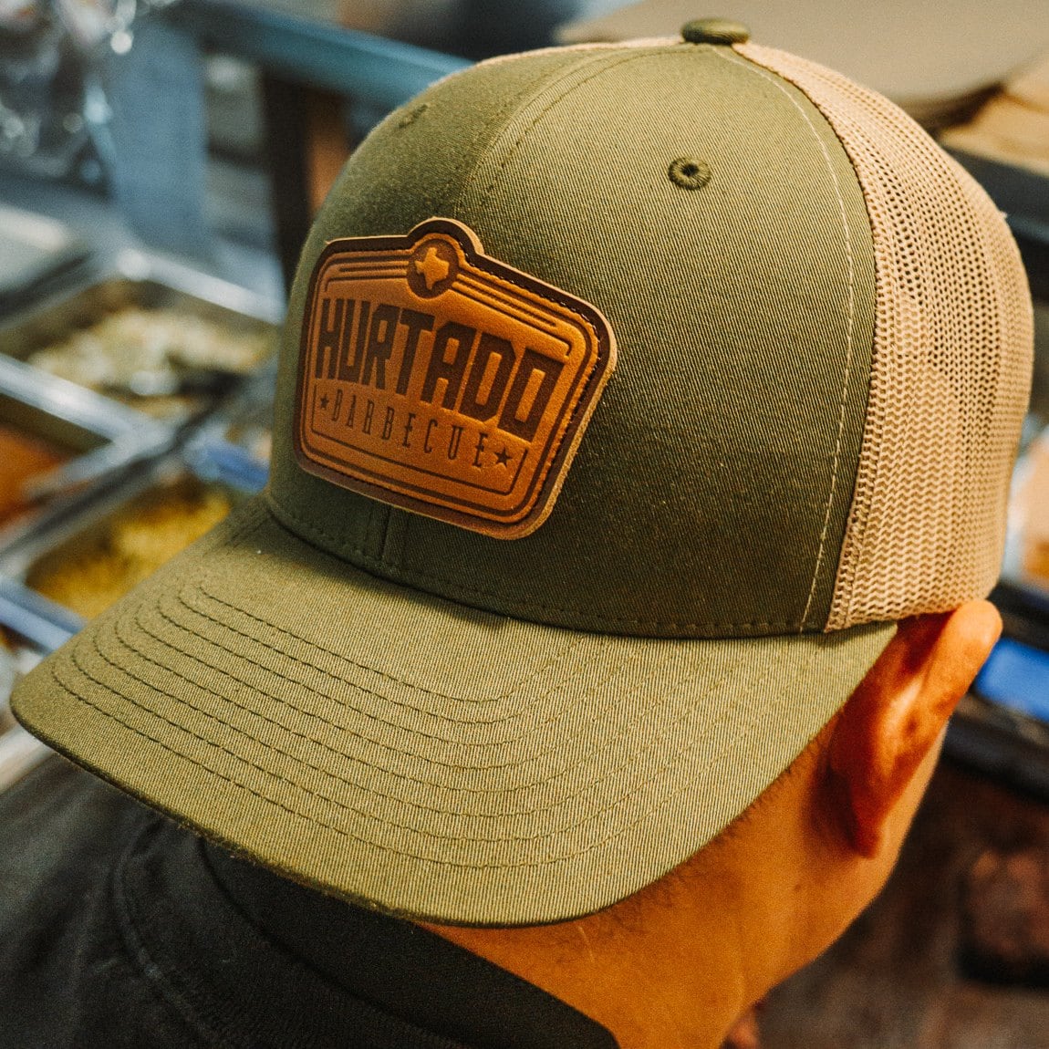 Leather Patch Trucker Hat in olive with a khaki mesh back and the Hurtado Barbecue leather patch